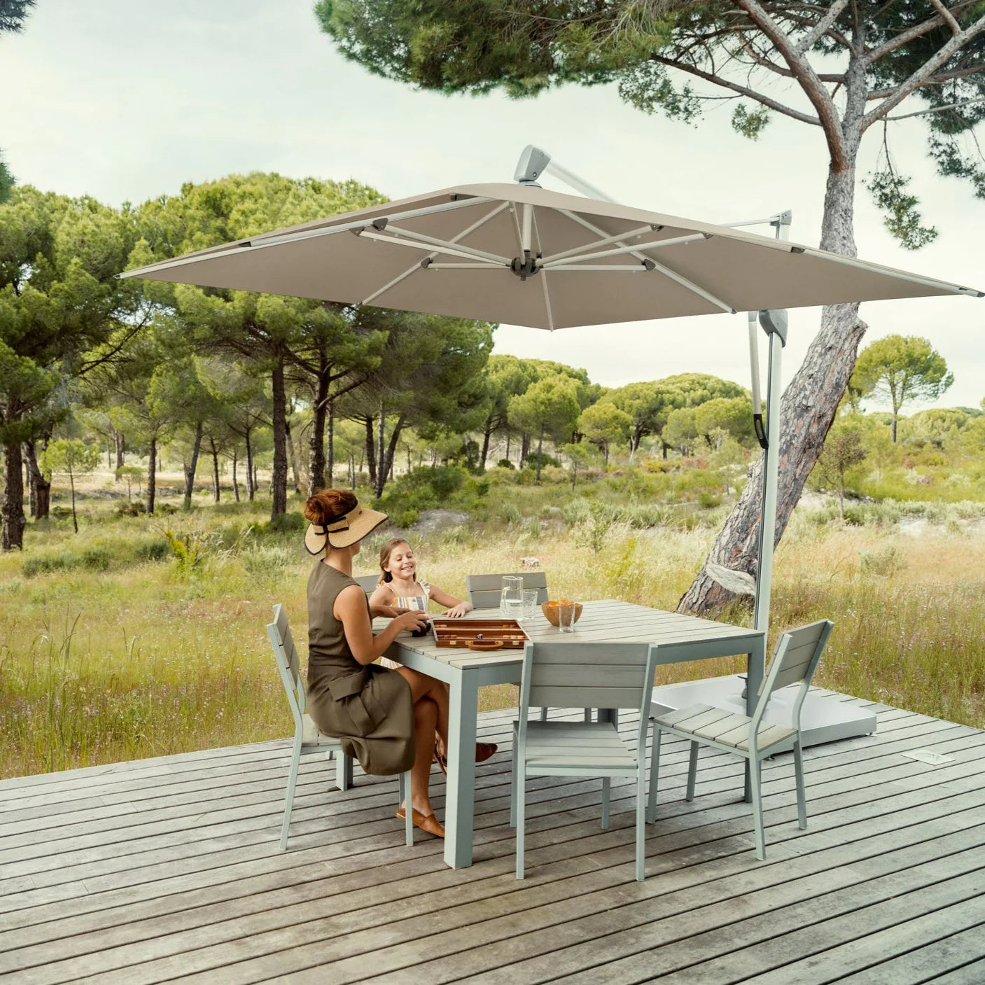 Glatz image of dining table and chairs on decking with a big parasol.