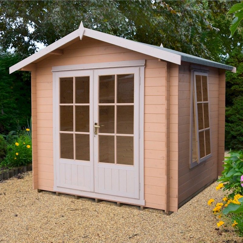 Shire 7x7 Barnsdale Log Cabin on gravel with trees in background and flowers in foreground.
